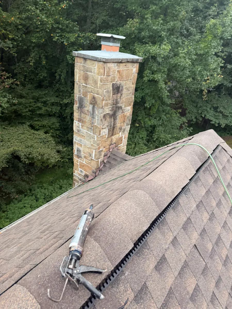 Roofing detail at a stone chimney and shingle ridge in McLean